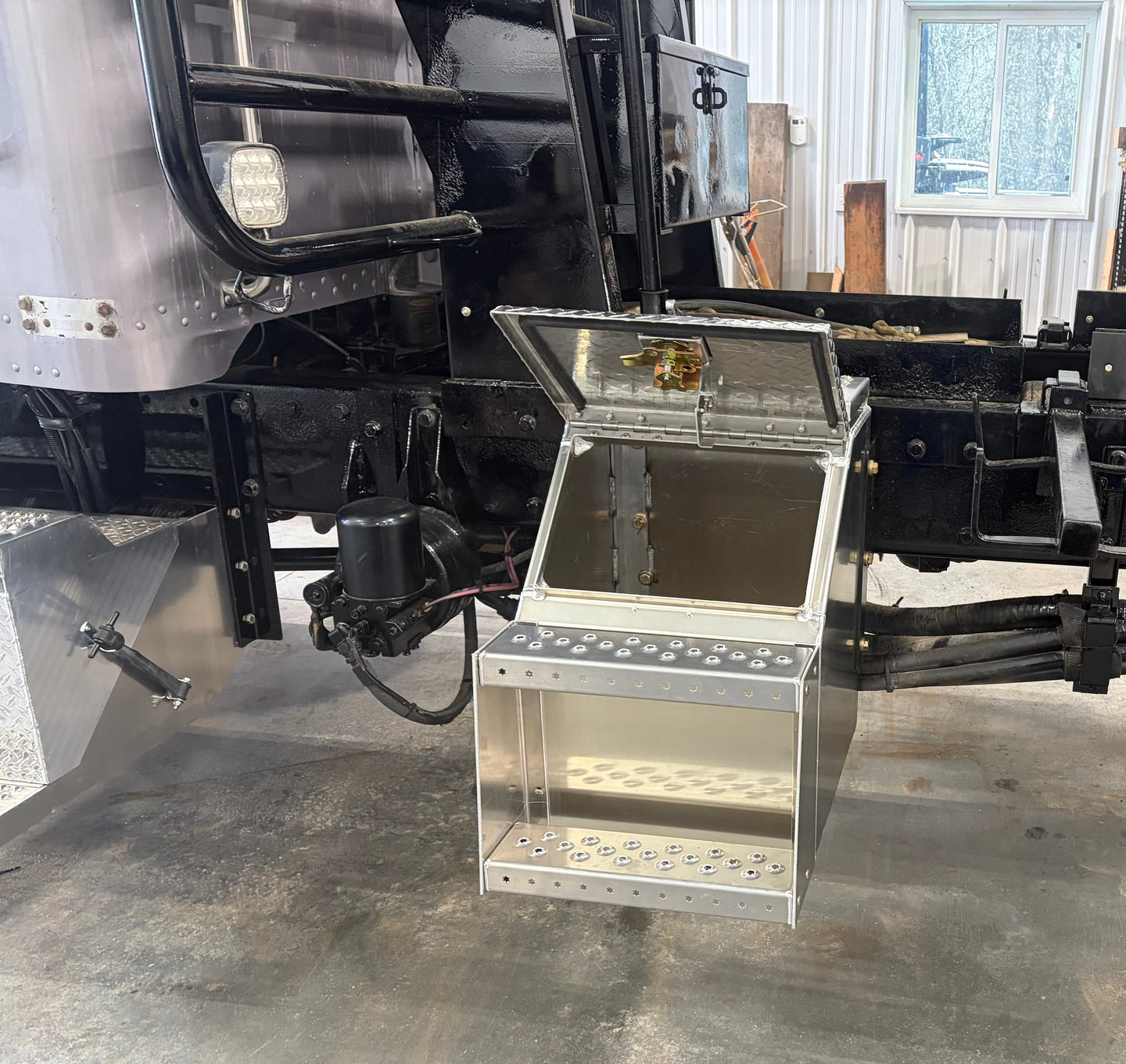 an open step box on a black truck frame in a shop