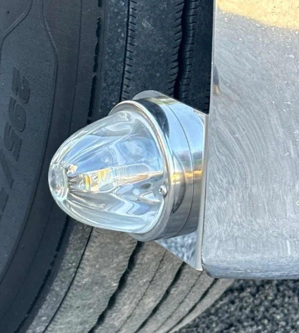 Close-up of a vehicle light fixture on a bumper with tire tread background